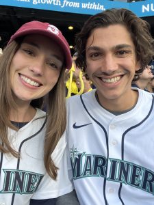 A woman and man in Mariners jerseys smiling together at T-Mobile Park during the ALCS game